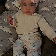 Athena joined the competition — help win amazing prizes! baby, child, infant, pink_bow, headband, floral_pants, sweater, cushion, cloud_pattern, sitting, indoors, curious, face, person, cute, comfortable, soft_lighting, portrait, cozy, sock