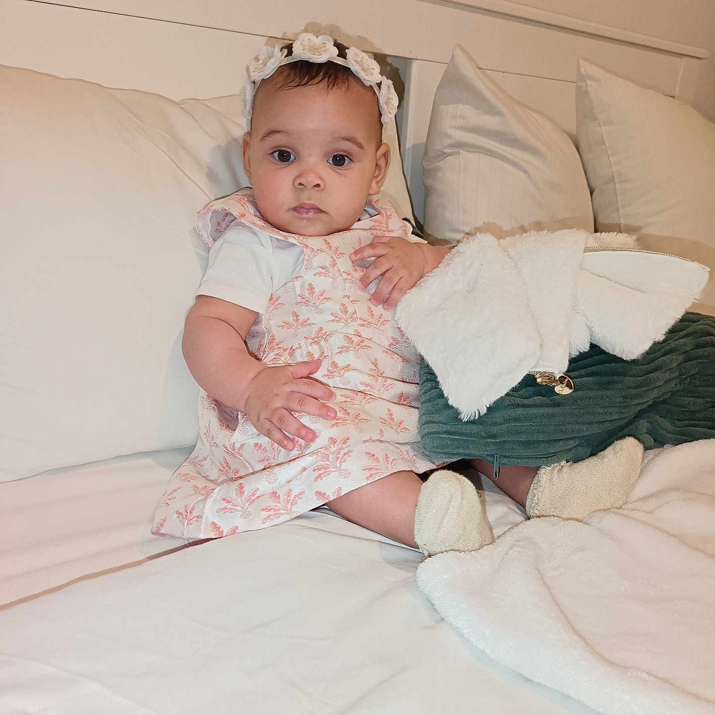 Hulda-Taali a rejoint le concours — aidez-le/la à gagner de superbes lots ! baby, bed, blanket, child, comfortable, cozy, curious, cute, dress, flower, headband, indoors, infant, person, pillow, pink, portrait, sitting, soft_toys, white