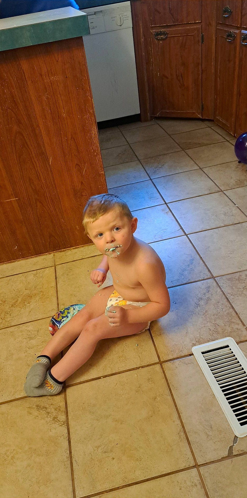 Mason is registered to the contest to win money with this photo: barechested, barefoot, cabinetry, calf, chest, floor, flooring, foot, hardwood, human_leg, joint, knee, leg, leisure, person, sandal, sitting, thigh, toddler, trunk