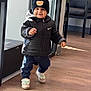 toddler, child, indoor, walking, black_jacket, beanie, hat, sneakers, floor, window, door, smiling, cute, clothing, person, young_child, happy, pants, footwear, headwear