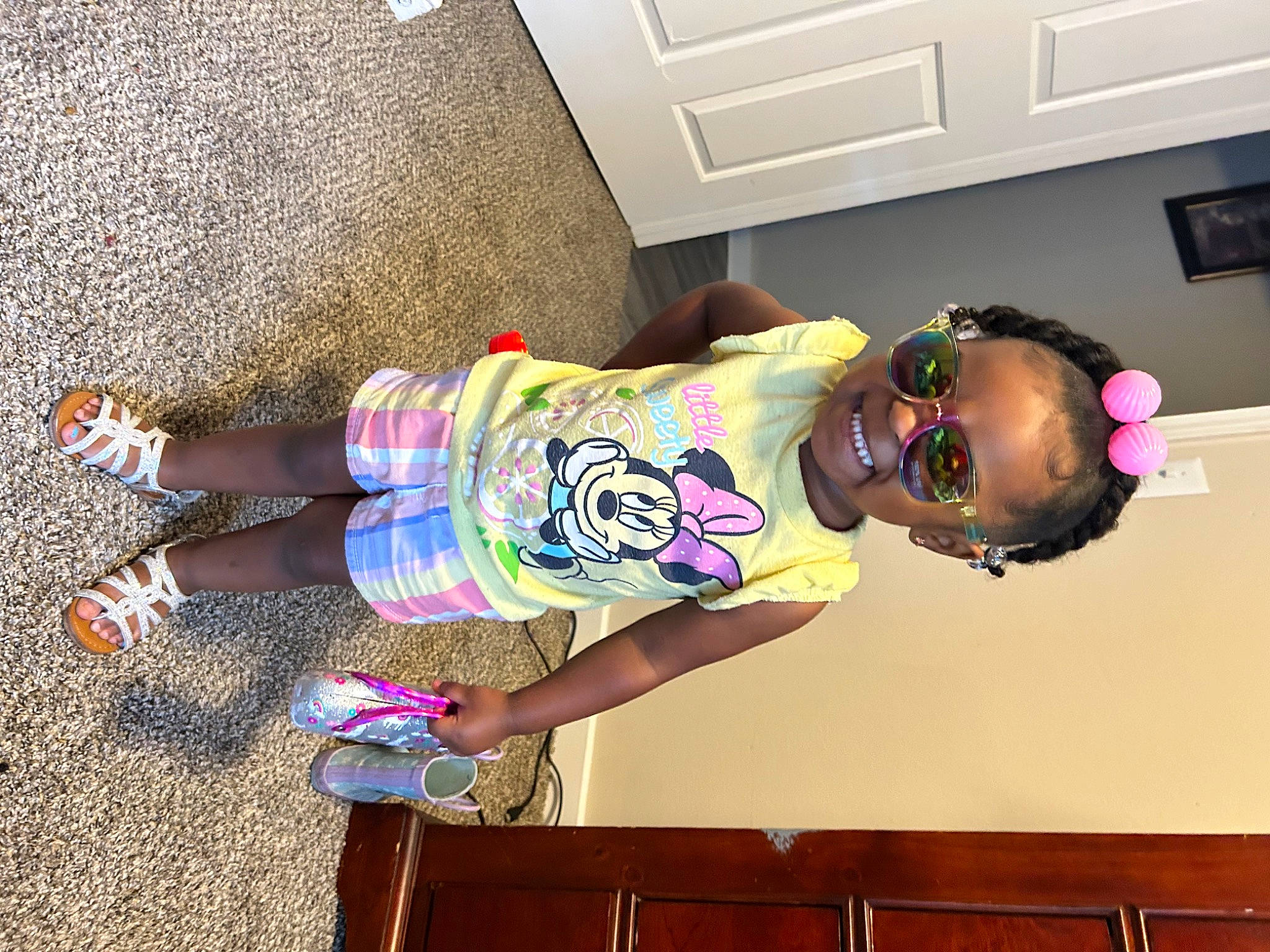 Stori is registered to the contest to win money with this photo: baby_toddler_clothing, cabinetry, child, eyewear, flooring, foot, fun, happy, human_leg, light_switch, magenta, pattern, person, pink, room, sandal, thigh, toddler