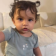 Azalea joined the competition — help win amazing prizes! toddler, child, curly_hair, pigtails, green_shirt, flower_print, indoor, couch, beige, soft_lighting, portrait, cute, young_child, person, face, expression, home, cozy, sitting, casual