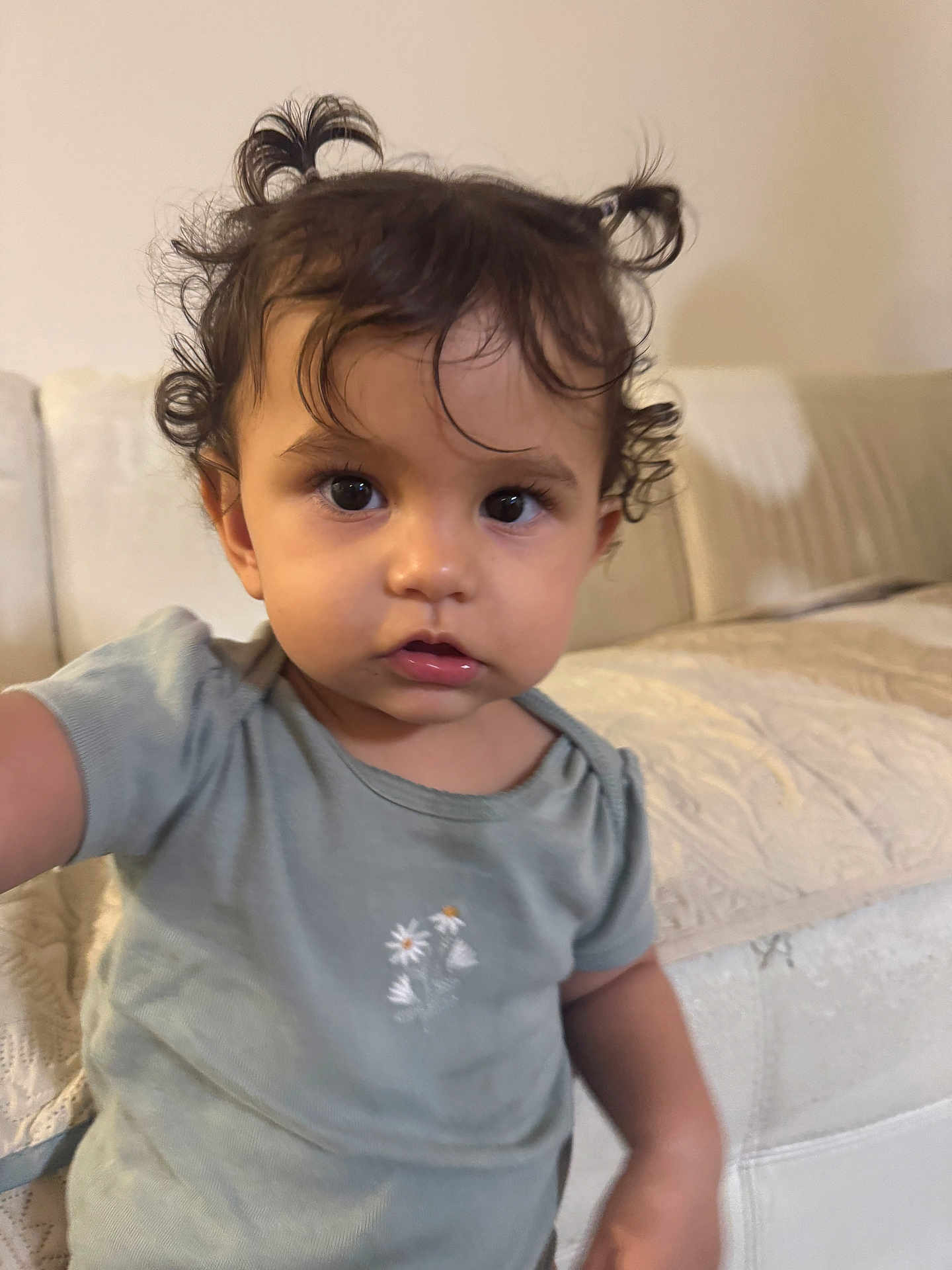 Azalea joined the competition — help win amazing prizes! toddler, child, curly_hair, pigtails, green_shirt, flower_print, indoor, couch, beige, soft_lighting, portrait, cute, young_child, person, face, expression, home, cozy, sitting, casual
