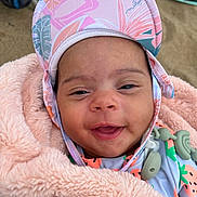 Eliana joined the competition — help win amazing prizes! baby, smiling, hat, blanket, infant, face, outdoor, cute, child, happy, apparel, headgear, person, portrait, skin, clothing, closeup, expression, babywear, sand