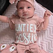 Madison is registered to the contest to win money with this photo: baby, blanket, bow, child, cute, face, flower_pattern, happy, headband, indoors, infant, lying_down, newborn, person, pink_clothing, portrait, skirt, smiling, soft_texture, toddler