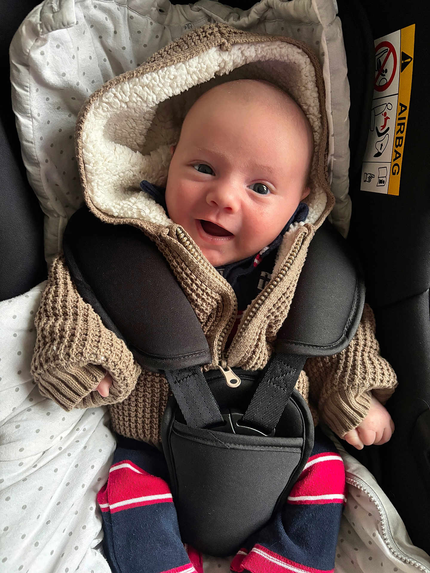 Maylo participe au concours pour gagner de l'argent avec cette photo : baby, child, car_seat, knitted_jacket, hood, smiling, happy, blanket, seatbelt, safety, infant, cute, warm_clothing, portrait, indoor, closeup, face, person, candid, cozy