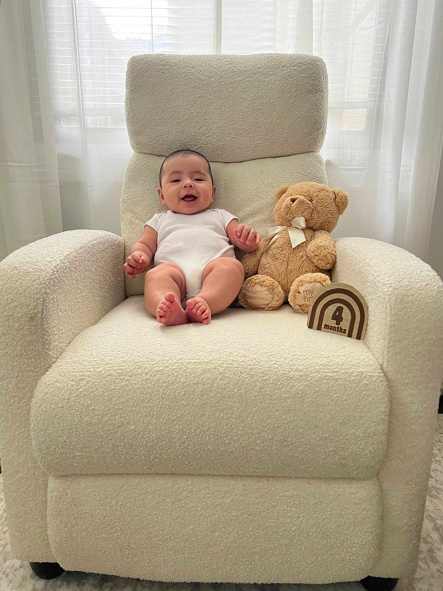 Nathan is registered to the contest to win money with this photo: baby, armchair, teddy_bear, wooden_sign, indoor, smiling, cozy, white, curtains, soft_light, child, infant, cute, furniture, sitting, plush_toy, home, portrait, comfortable, decor