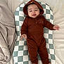 Nathan joined the competition — help win amazing prizes! baby, infant, child, hoodie, brown_clothing, pillow, checkered_pattern, bed, blanket, smiling, cute, cozy, sleepwear, foot, hand, face, indoors, soft_fabric, lying_down, playful