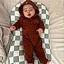 Nathan joined the competition — help win amazing prizes! baby, infant, onesie, hood, checkered_cushion, bed, blanket, sleepwear, cute, child, foot, hand, expression, indoors, resting, person, soft_fabric, comfortable, sleeping_area, cozy