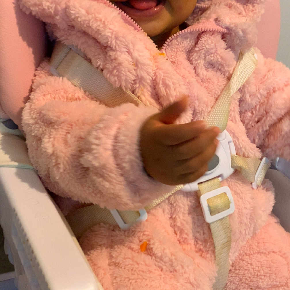 Daïanna participe au concours pour gagner de l'argent avec cette photo : baby, child, closeup, clothing, cute, face, fluffy, hand, happy, high_chair, hood, indoor, infant, person, pink_onesie, portrait, safety_straps, seat, smiling, tongue_out