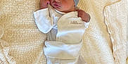 Ilyan participe au concours pour gagner de l'argent avec cette photo : baby, newborn, infant, hat, striped_hat, clothing, white_clothes, blanket, cream_blanket, soft_texture, lying_down, indoors, cute, face, person, baby_clothes, cozy, small, sleepwear, infant_baby