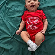 Henry joined the competition — help win amazing prizes! baby, child, cute, face, green_blanket, happy, human, indoor, infant, lying_down, person, portrait, red_onesie, skin, small, smiling, socks, soft_texture, text_on_clothing, young