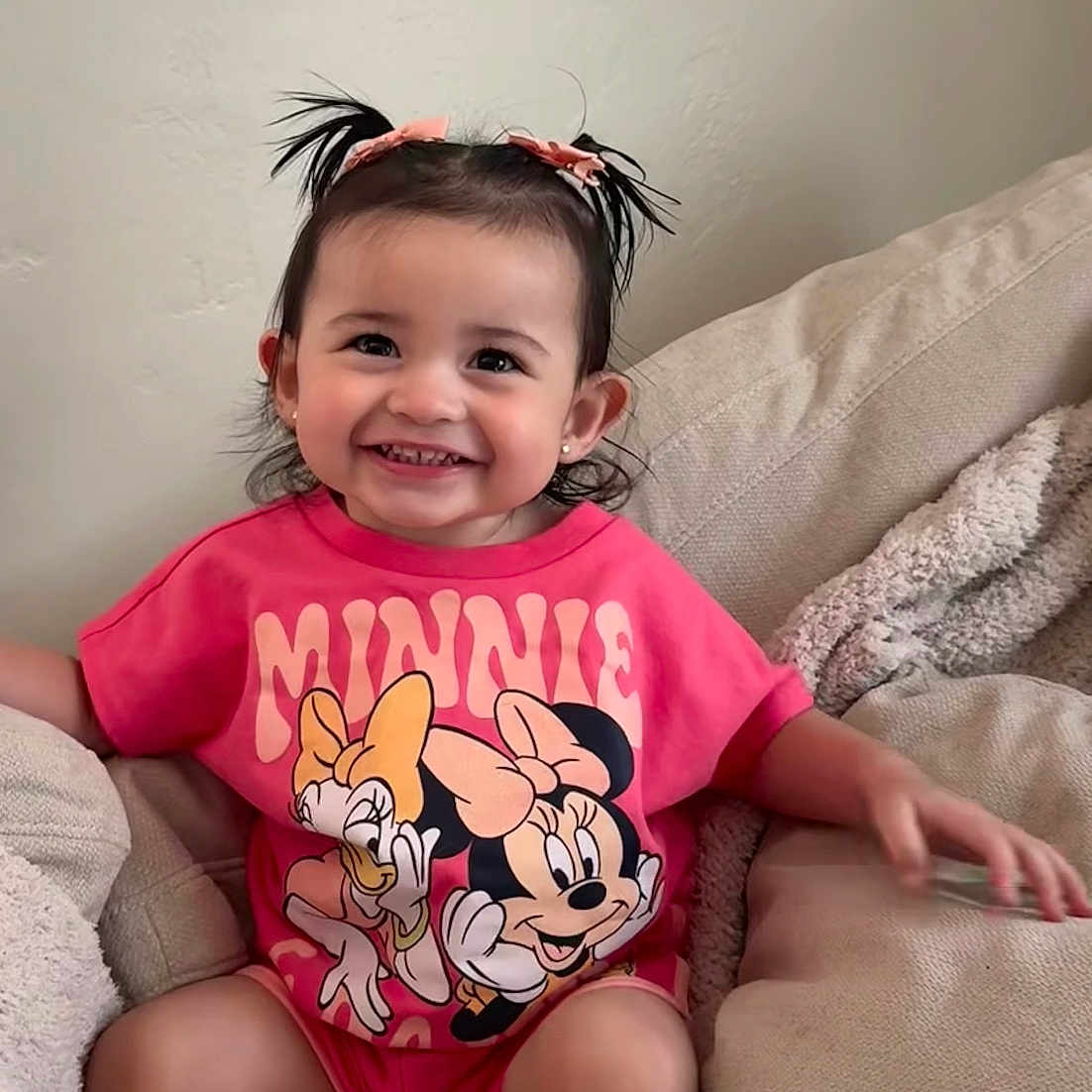 Alexus is registered to the contest to win money with this photo: child, toddler, smiling, sitting, pink_shirt, minnie_mouse, pigtails, couch, cozy, blanket, indoors, cute, happy, person, face, hair_bow, white_socks, casual, comfortable, portrait
