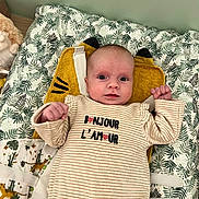 Luna a rejoint le concours — aidez-le/la à gagner de superbes lots ! baby, infant, newborn, onesie, striped_clothing, text_on_clothes, leaf_pattern, bedding, pillow, yellow_pillow, stuffed_animal, face, eyes, hands, crib, nursery, blanket, portrait, alert_expression, cozy