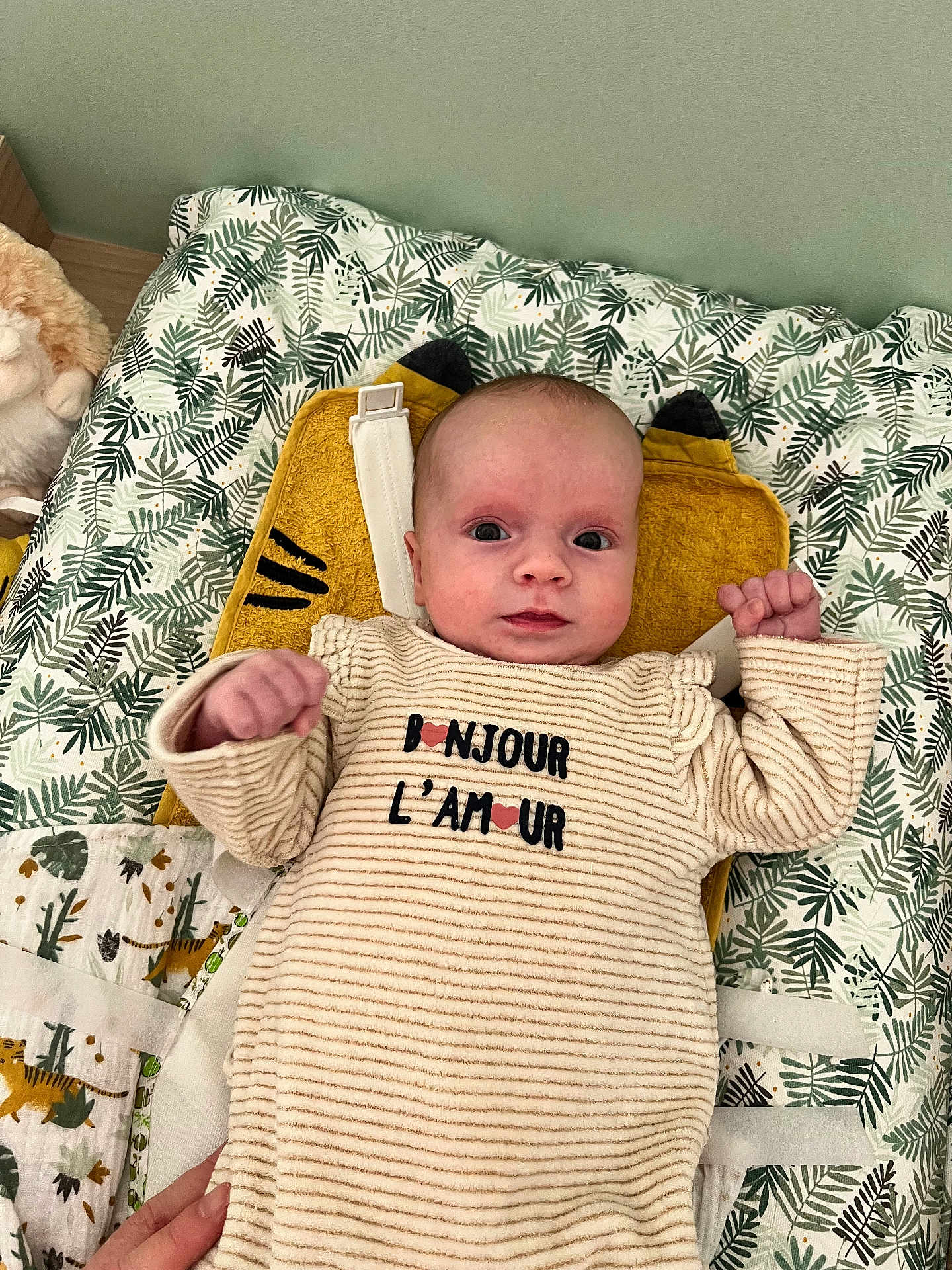 Luna a rejoint le concours — aidez-le/la à gagner de superbes lots ! baby, infant, newborn, onesie, striped_clothing, text_on_clothes, leaf_pattern, bedding, pillow, yellow_pillow, stuffed_animal, face, eyes, hands, crib, nursery, blanket, portrait, alert_expression, cozy
