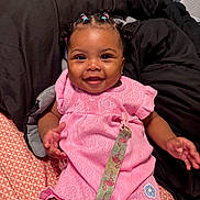 Kyomi joined the competition — help win amazing prizes! baby, child, smiling, pink_clothing, pacifier_clip, bed, blanket, patterned_sheet, cute, happy, indoors, person, portrait, infant, braided_hair, earrings, decorative_clothing, seated, black_blanket, colorful