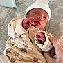 newborn, baby, infant, sleeping, hat, pajamas, hand, adult_hand, bed, blanket, soft, cozy, cute, peaceful, resting, indoor, clothing, person, portrait, child