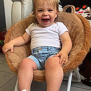 Erwann participe au concours pour gagner de l'argent avec cette photo : chair, child, cushion, cute, denim_shorts, floor_tiles, footwear, furniture, happy, home, indoor, person, plush_chair, seated, short_hair, smiling, sneakers, toddler, toy_car, white_tshirt