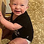 baby, child, smiling, sitting, black_shirt, diaper, floor, wooden_surface, happy, cute, infant, indoor, person, face, skin, legs, arms, expression, young, playful
