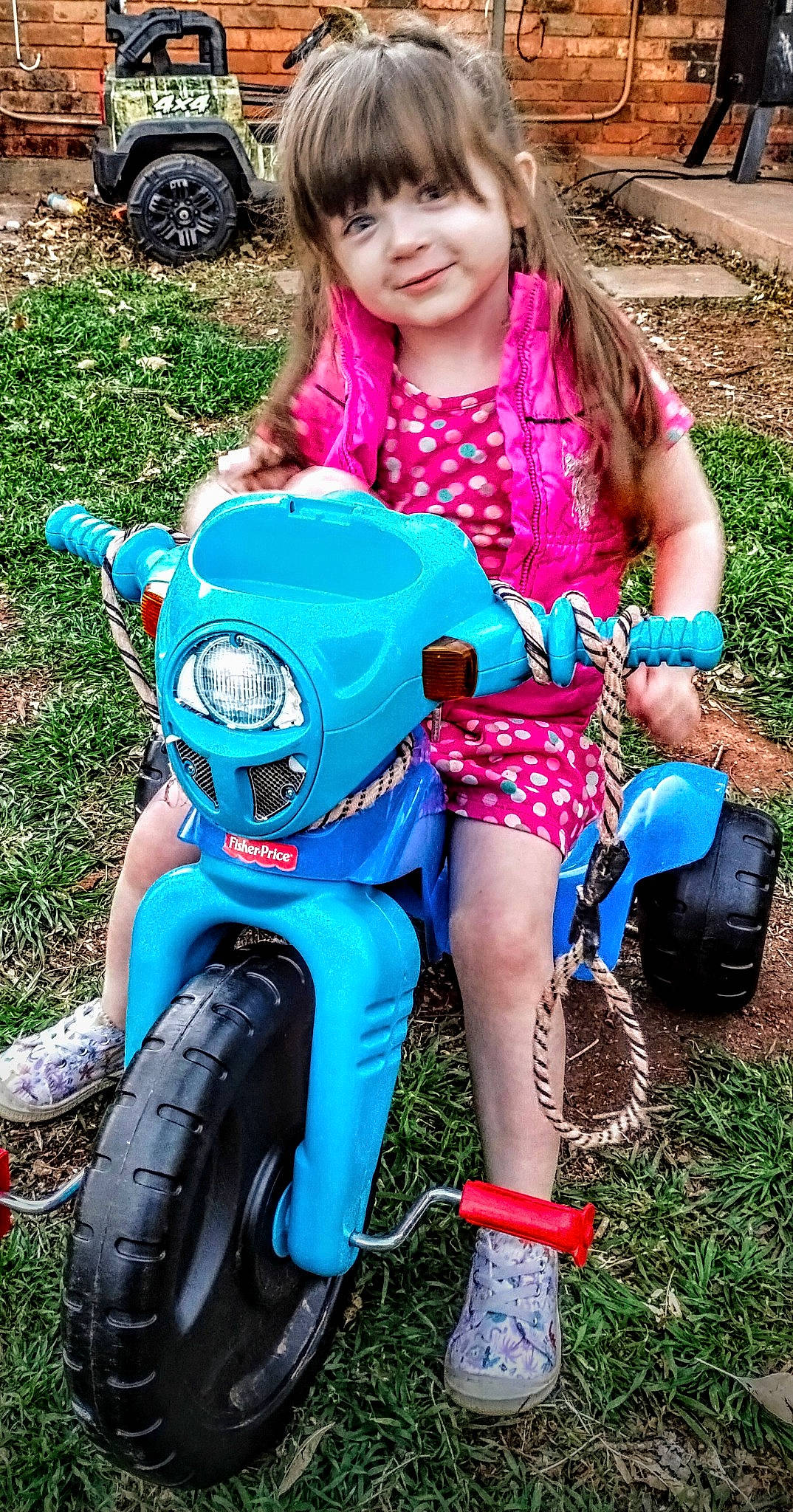 Mckenna is registered to the contest to win money with this photo: automotive_tire, baby_toddler_clothing, blue, cool, fender, fun, grass, green, happy, joy, motor_vehicle, person, photograph, pink, red, riding_toy, shoe, smile, sneakers, summer