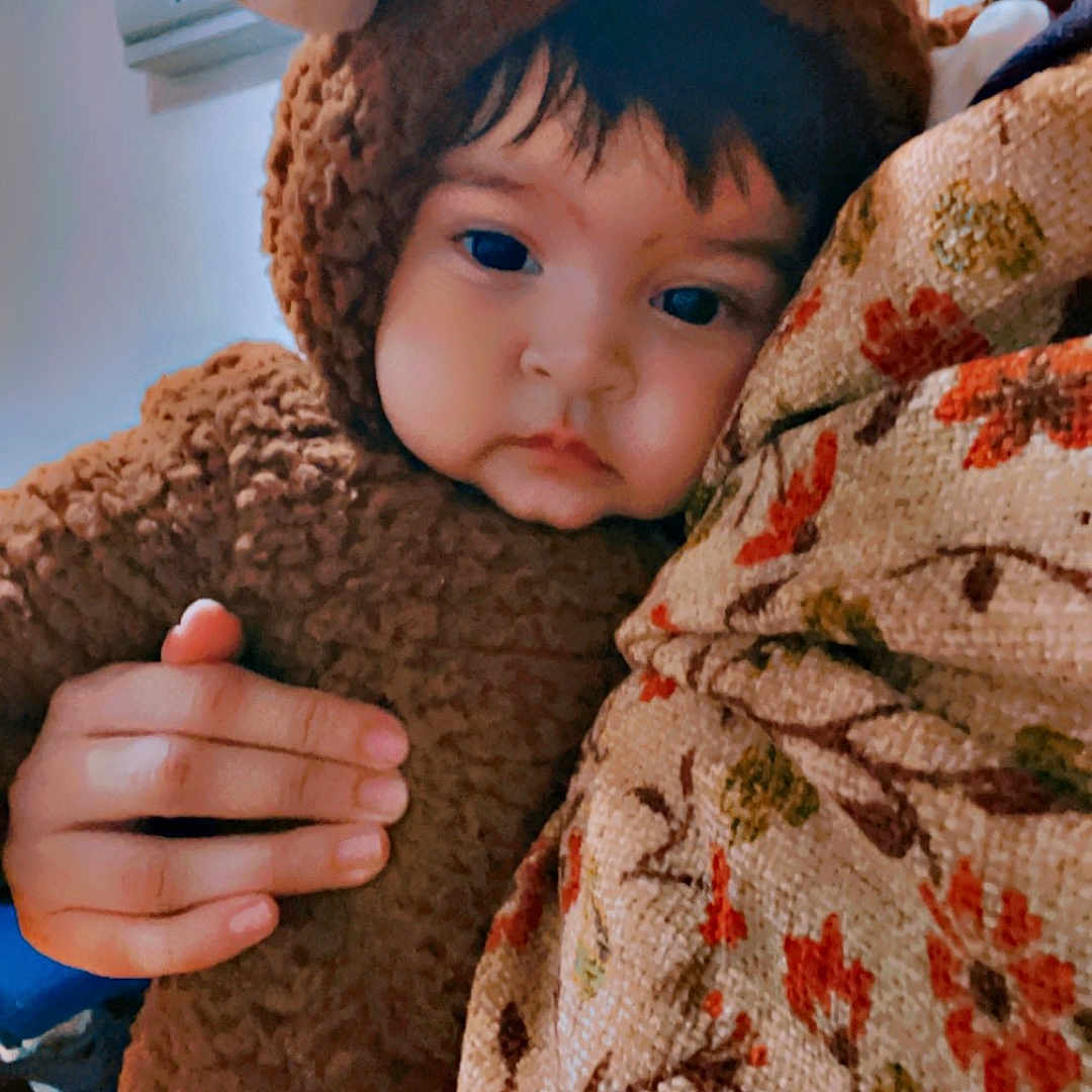 Zimal is registered to the contest to win money with this photo: baby, blanket, bodypart, bonnet, cap, clothing, face, finger, hand, happy, hat, head, hoodie, knitwear, person, photography, portrait, smile, sweater, sweatshirt