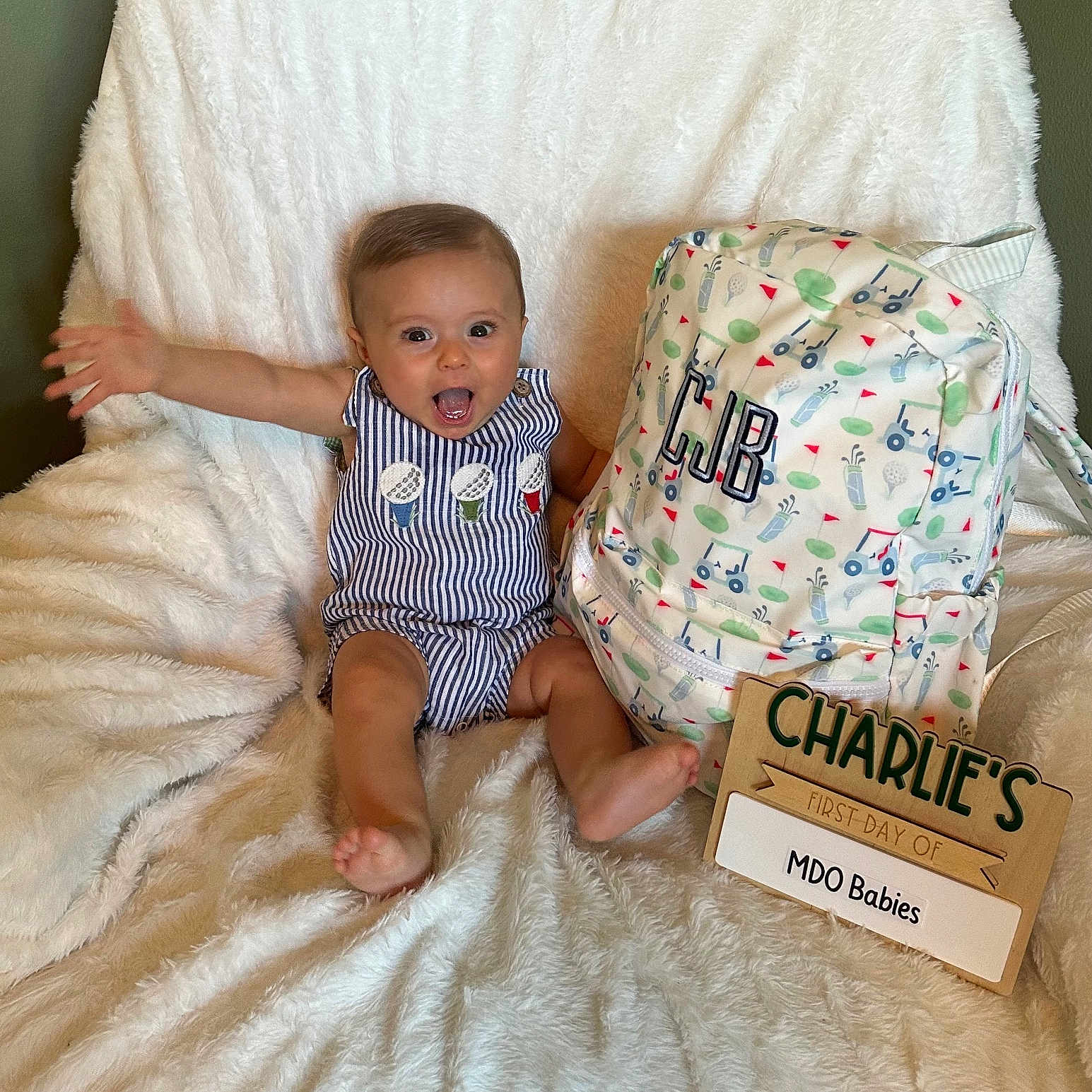 Charles joined the competition — help win amazing prizes! baby, backpack, bright, cheerful, child, clothing, cute, face, fluffy_blanket, happy, home, indoor, infant, person, portrait, sitting, small_child, smiling, striped_romper, wooden_sign