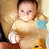 awake, baby, baby_seat, bib, blanket, blue_eyes, cheeks, closeup, fur, gaze, hand, infant, pink_clothing, plush, portrait, rattle, sleeve, soft_lighting, stuffed_toy, toy