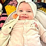 baby, baby_girl, blanket, blue_eyes, bouncer, bow, close_up, cozy, cute, fabric_pattern, happy, headband, indoor, infant, onesie, portrait, rosy_cheeks, smile, soft_toy, stuffed_animal