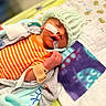 newborn, baby, infant, sleeping, hospital, medical, pacifier, knit_cap, onesie, blanket, crib, bed, face, hand, wristband, tubing, monitor, orange, portrait, indoors