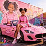 Zi'Sha is registered to the contest to win money with this photo: child, girl, smiling, portrait, outdoor, street, graffiti, pink_car, convertible, barbie, fashion, pink_outfit, jacket, skirt, sneakers, braids, hairstyle, boombox, spray_paint, urban_scene