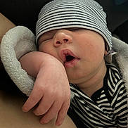 Castillo is registered to the contest to win money with this photo: baby, sleeping, hat, striped_clothing, blanket, arm, mouth_open, closeup, peaceful, newborn, infant, soft_texture, resting, cozy, human, skin, portrait, baby_clothes, indoor, relaxation