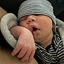 baby, sleeping, hat, striped_clothing, blanket, arm, mouth_open, closeup, peaceful, newborn, infant, soft_texture, resting, cozy, human, skin, portrait, baby_clothes, indoor, relaxation