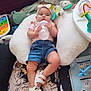 Addisyn is registered to the contest to win money with this photo: baby, infant, bottle, headband, pillow, denim_shorts, sandals, toy, carpet, floor, child, cute, indoors, clothing, person, playtime, comfort, relaxing, pink, colorful