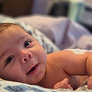 Elijah is registered to the contest to win money with this photo: baby, infant, face, skin, blanket, lying_down, cute, portrait, child, expression, soft, indoor, newborn, closeup, person, sleepwear, young, smile, resting, warm