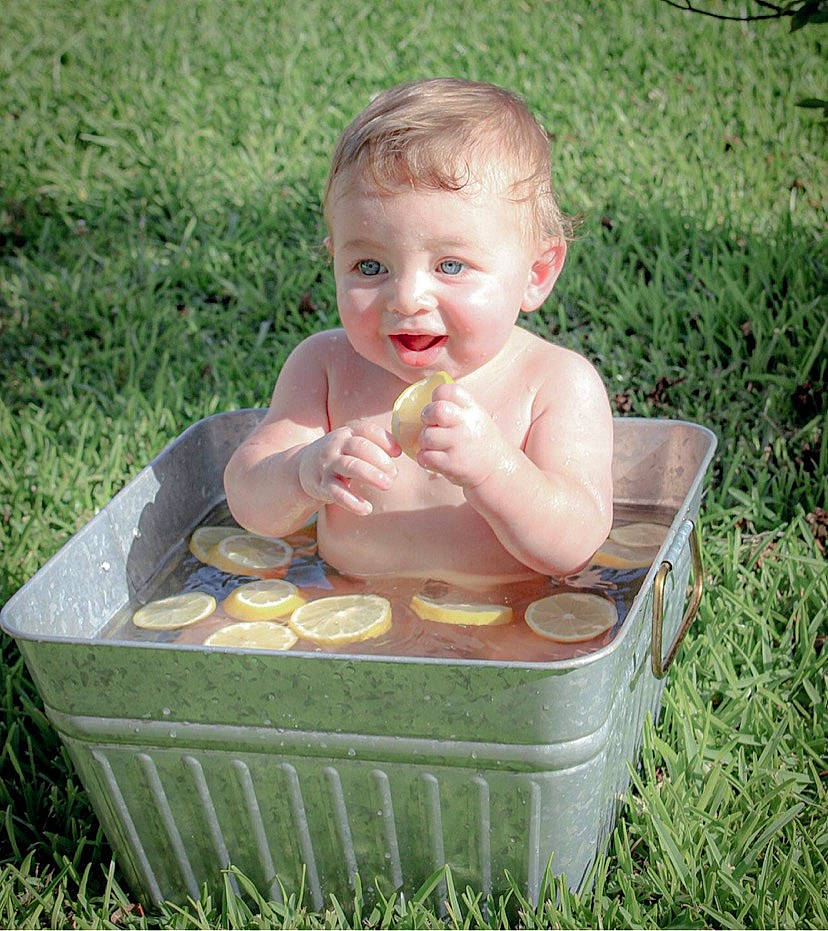 Hudson is registered to the contest to win money with this photo: baby, baby_products, baby_toddler_clothing, basket, bathing, cheek, child, foot, fun, grass, happy, leisure, people_in_nature, person, plant, recreation, sitting, smile, thumb, toddler