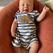 Andréa a rejoint le concours — aidez-le/la à gagner de superbes lots ! baby, infant, smiling, winking, striped_clothing, onesie, koala_design, cushion, rust_color, relaxing, indoor, cute, happy, child, person, skin, head, legs, arm, comfort