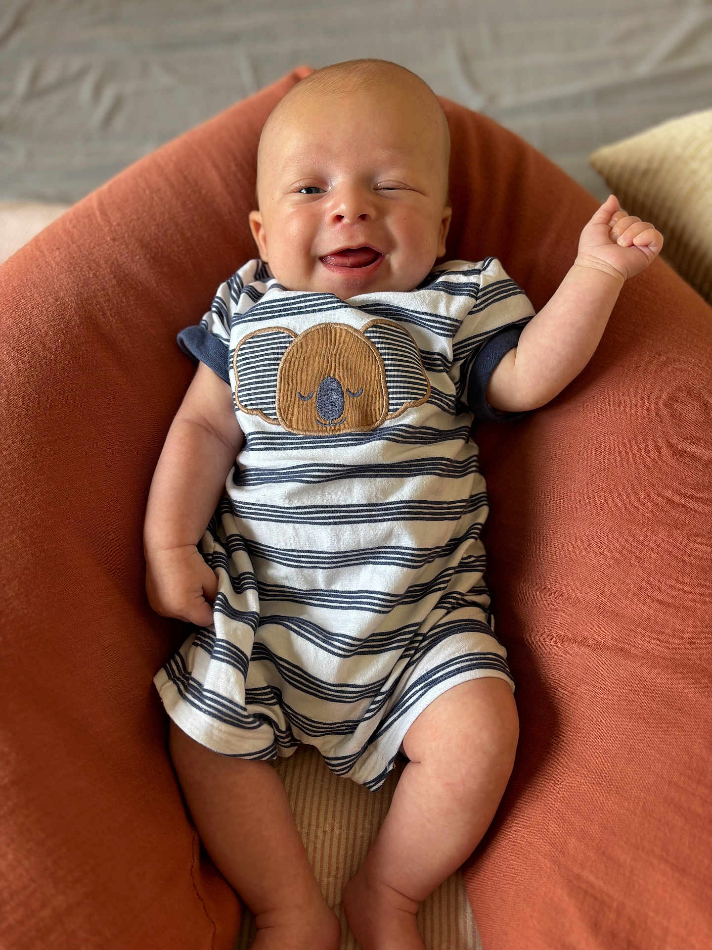 Andréa a rejoint le concours — aidez-le/la à gagner de superbes lots ! baby, infant, smiling, winking, striped_clothing, onesie, koala_design, cushion, rust_color, relaxing, indoor, cute, happy, child, person, skin, head, legs, arm, comfort