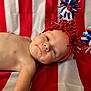 Jace joined the competition — help win amazing prizes! baby, infant, red_headband, pom_poms, striped_fabric, face, skin, lying_down, portrait, celebration, festive, closeup, cheerful, child, cute, headwear, indoors, smiling, red, white