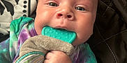 Jace joined the competition — help win amazing prizes! baby, infant, teething_toy, tie_dye_clothing, hand, face, blue_eyes, blanket, patterned_blanket, quilted_blanket, cute, close_up, child, young_child, soft_skin, indoor, person, lying_down, colorful_clothing, exploration