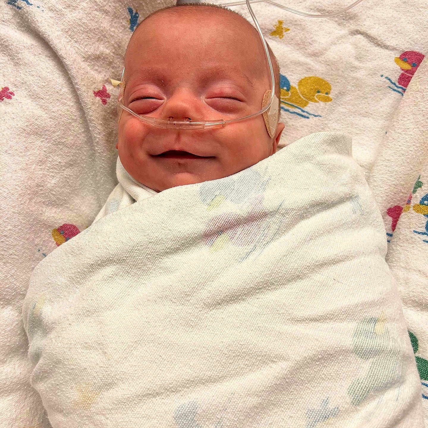 Ryet joined the competition — help win amazing prizes! baby, blanket, cute, duck_pattern, face, head, healthcare, hospital, infant, lying_down, medical, nasal_cannula, newborn, peaceful, person, sleeping, smile, soft_texture, swaddled, wrapped