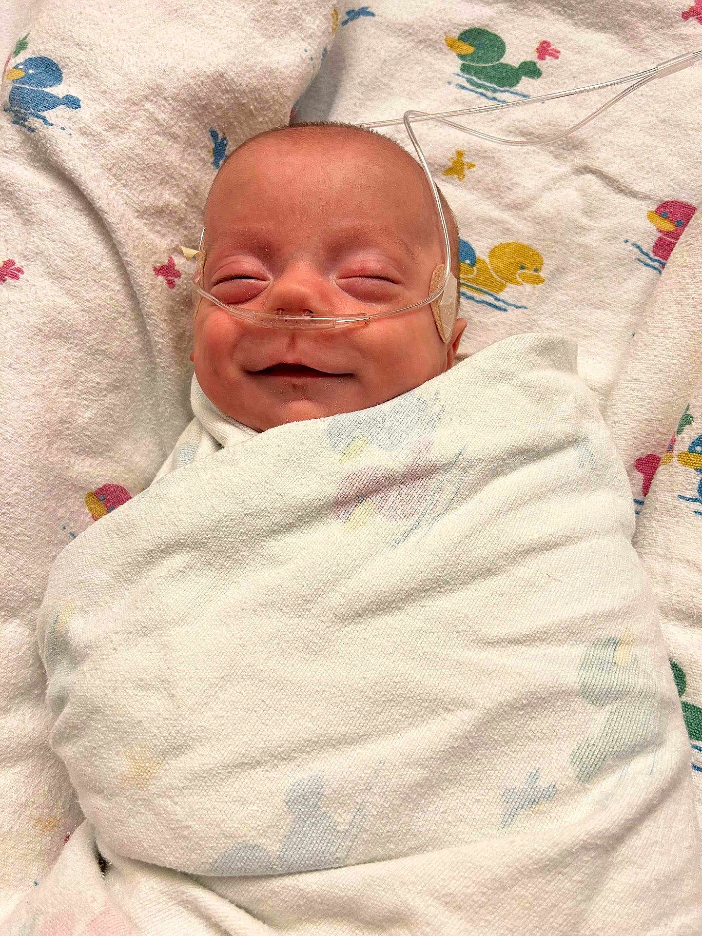 Ryet joined the competition — help win amazing prizes! baby, blanket, cute, duck_pattern, face, head, healthcare, hospital, infant, lying_down, medical, nasal_cannula, newborn, peaceful, person, sleeping, smile, soft_texture, swaddled, wrapped