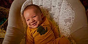 Bryce is registered to the contest to win money with this photo: baby, infant, smiling, yellow_outfit, dinosaur_design, baby_seat, cushion, patterned_fabric, cozy, indoors, child, happy, cute, relaxed, portrait, person, soft_lighting, small_child, baby_clothes, seated