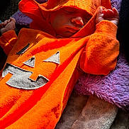 Bryce is registered to the contest to win money with this photo: baby, sleeping, hoodie, orange, pumpkin, blanket, cozy, child, infant, cute, clothing, resting, soft, warm, indoor, portrait, closeup, festive, holiday, comfort
