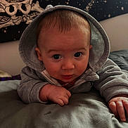 Bryce joined the competition — help win amazing prizes! baby, bed, blanket, child, clothing, cozy, curious, cute, expression, face, hand, hoodie, indoors, infant, person, portrait, skeleton, skin, stars, tapestry