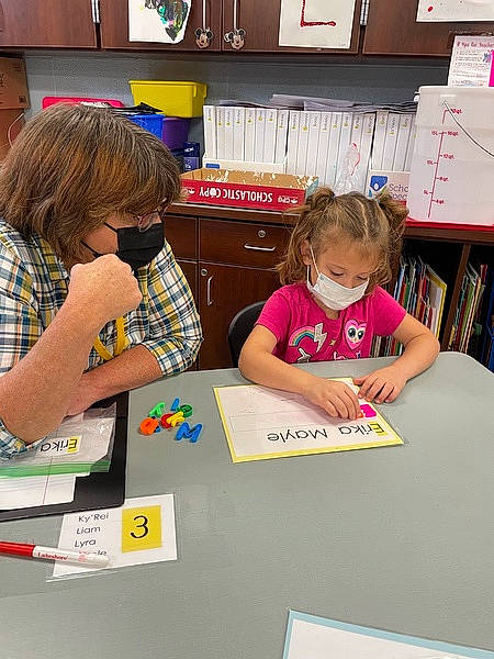 Erika is registered to the contest to win money with this photo: art, chair, child, community, desk, education, flooring, fun, homework, leisure, people, person, sharing, shelf, stationery, summer, t_shirt, table, toddler, writing