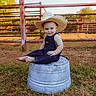 Alexander is registered to the contest to win money with this photo: toddler, child, cowboy_hat, denim_overalls, barefoot, metal_bucket, grass, fence, outdoor, farm, sunlight, smiling, portrait, rustic, nature, person, grassland, cute, baby, playful