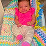 baby, cheerful, child, colorful_blanket, cozy, crocheted_blanket, cute, floor, happy, indoor, infant, lying_down, pink_shirt, portrait, small_hands, smile, socks, soft_texture, striped_clothing, toddler