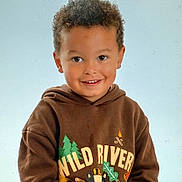 Dion joined the competition — help win amazing prizes! child, smiling, hoodie, brown_clothing, curly_hair, portrait, indoor, young_child, happy, face, casual_wear, person, cute, studio_lighting, childhood, sweatshirt, graphic_clothing, light_background, close_up, friendly