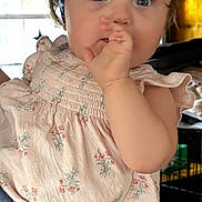 Willow is registered to the contest to win money with this photo: baby, child, infant, headband, dress, floral_pattern, hand, thumb, face, blue_eyes, curious, person, indoor, window, curtains, adult_hand, holding, soft_lighting, cozy, portrait