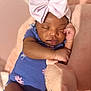 baby, sleeping, bow, headband, blue_onesie, pink_flowers, plush_toy, cuddling, soft_toy, infant, peaceful, cozy, pink_background, cute, child, portrait, closeup, resting, indoors, adorable